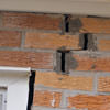 A brick wall displaying stair-step cracks and messy tuckpointing on a Kingsport home